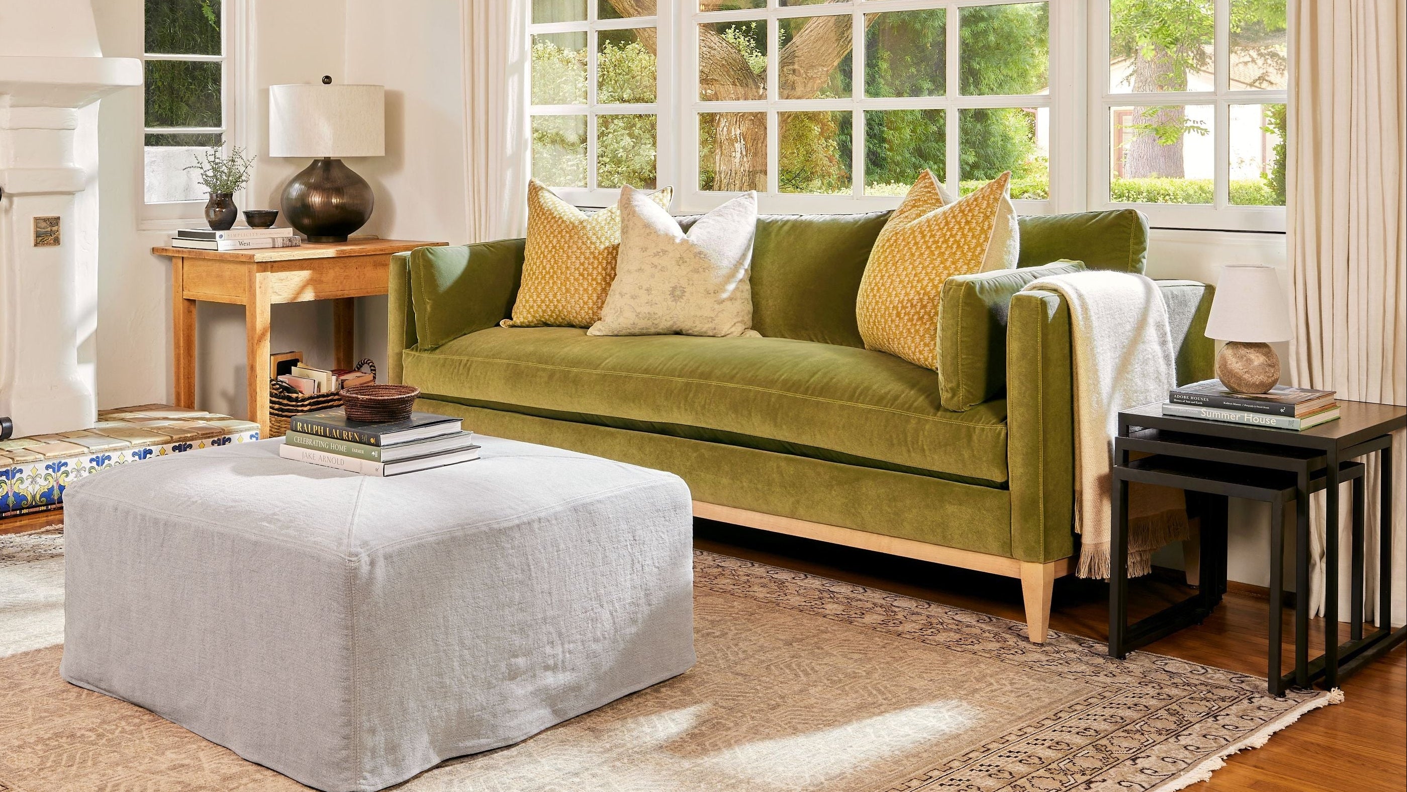 Living room with green sofa, white armchair, and large windows.