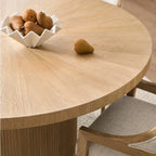Wooden dining table with a bowl of fruit on a light-colored surface