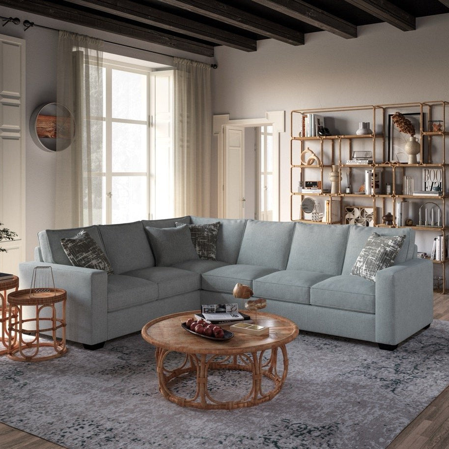 Modern living room with a gray sectional sofa, wooden coffee table, and bookshelf.