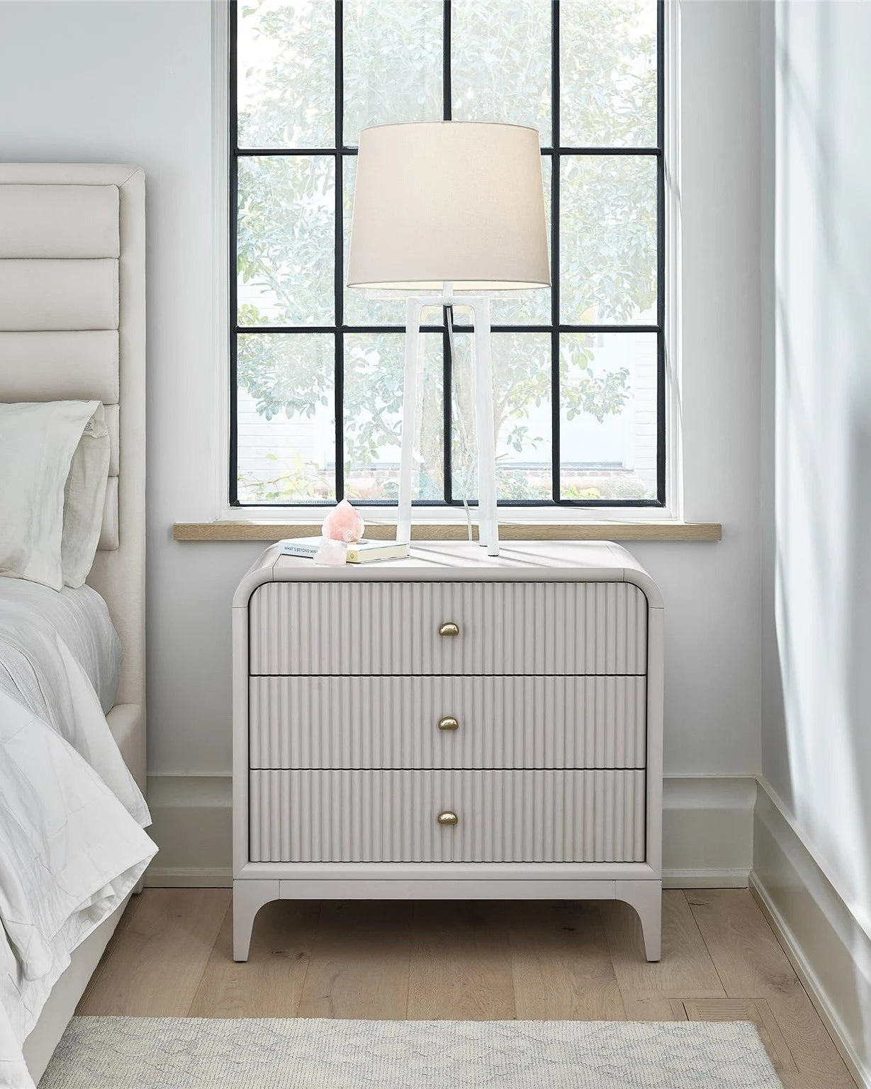 Neatly arranged bedroom with a bed and nightstand near a window.