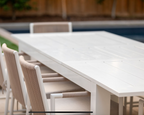 White outdoor dining table with chairs near a pool