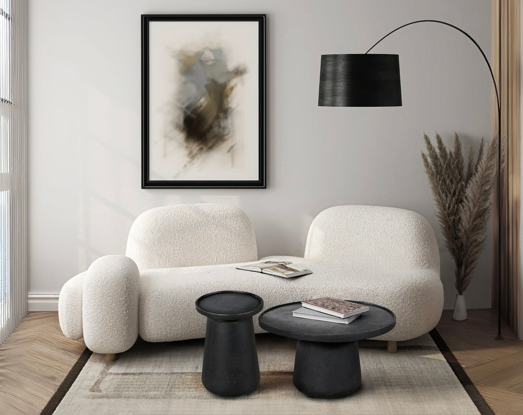 Modern living room with a white sofa, black tables, and decorative elements.