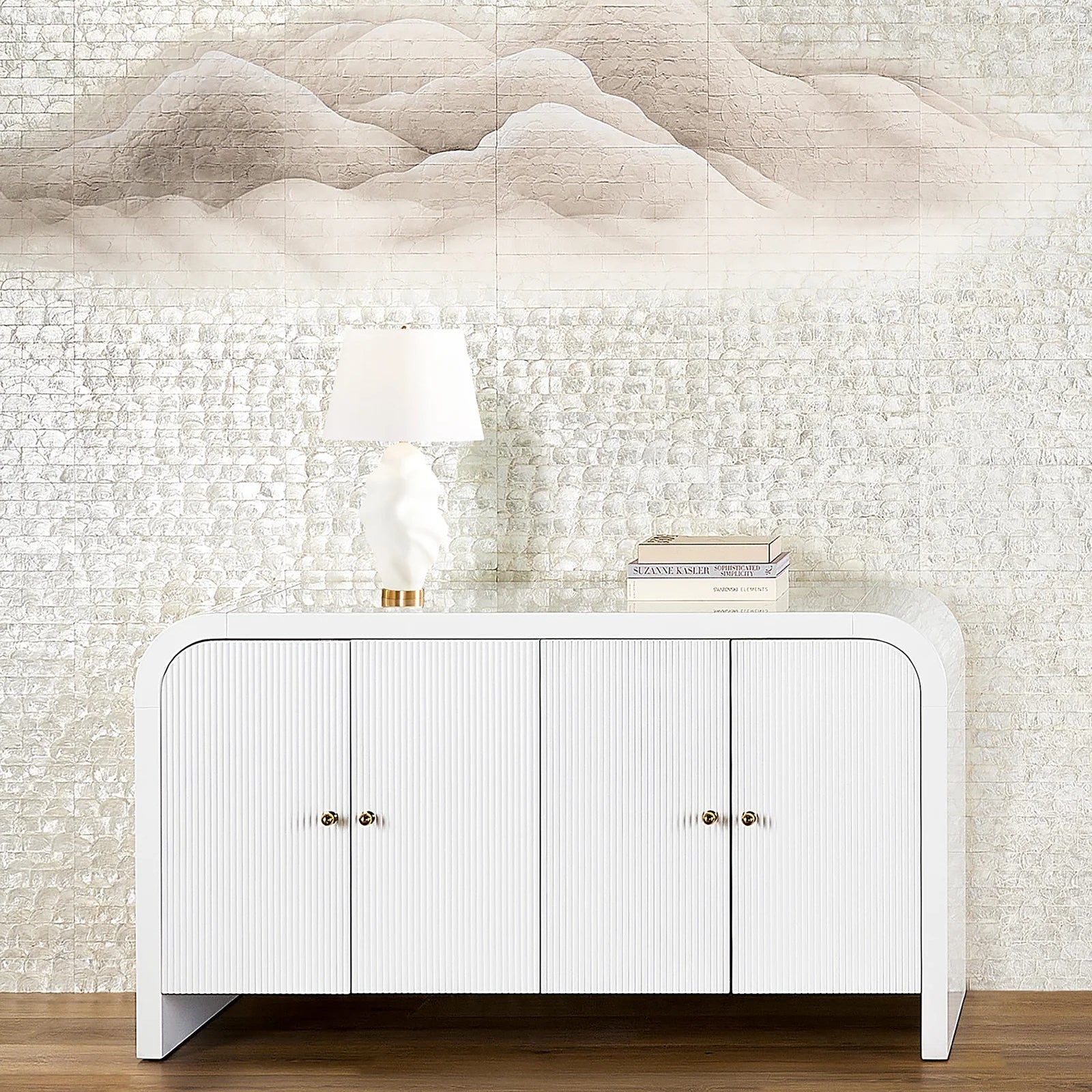White sideboard with gold handles against a textured wall.