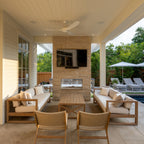 Outdoor patio area with furniture and a television mounted on a brick wall.