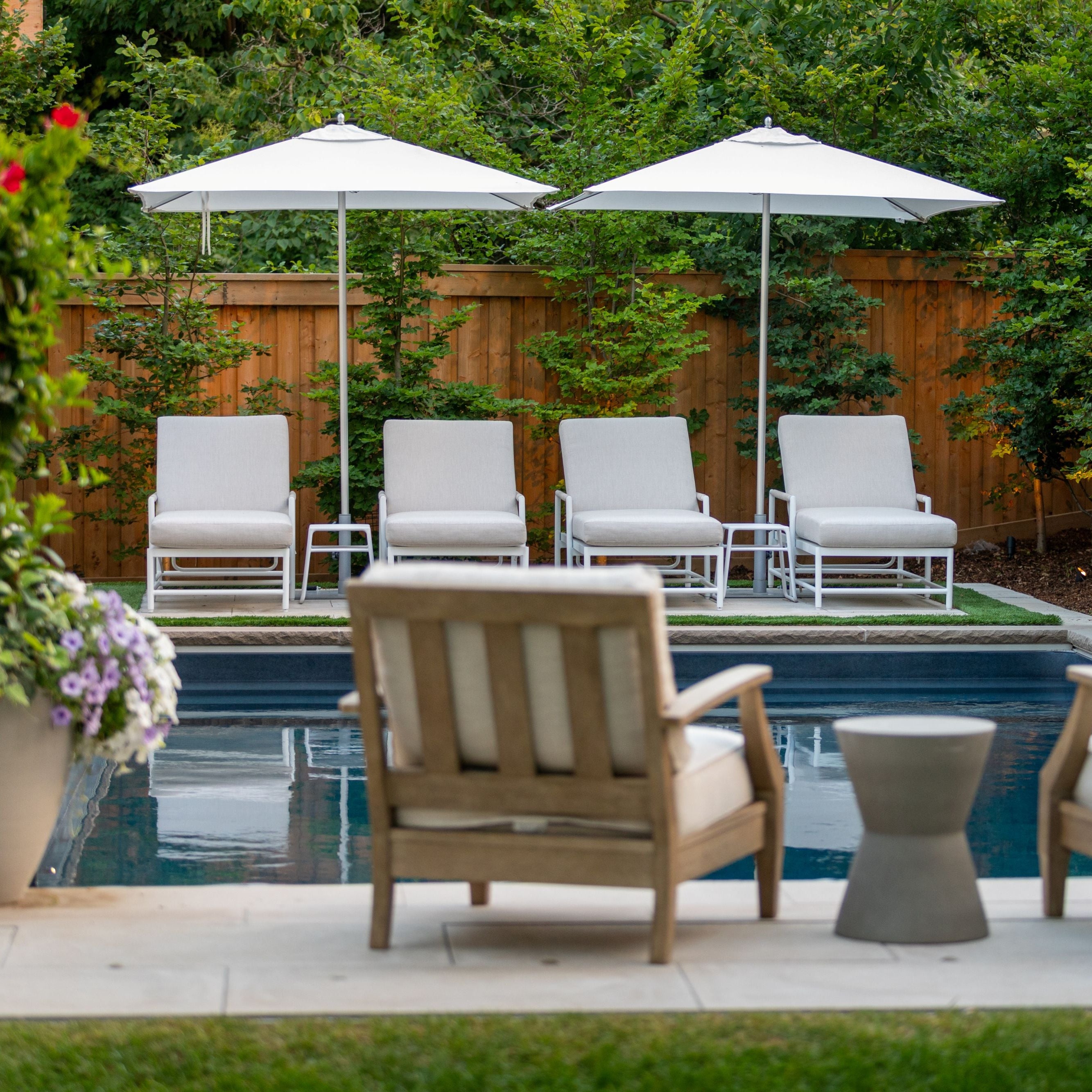 Outdoor seating area with chairs, tables, and umbrellas by a pool