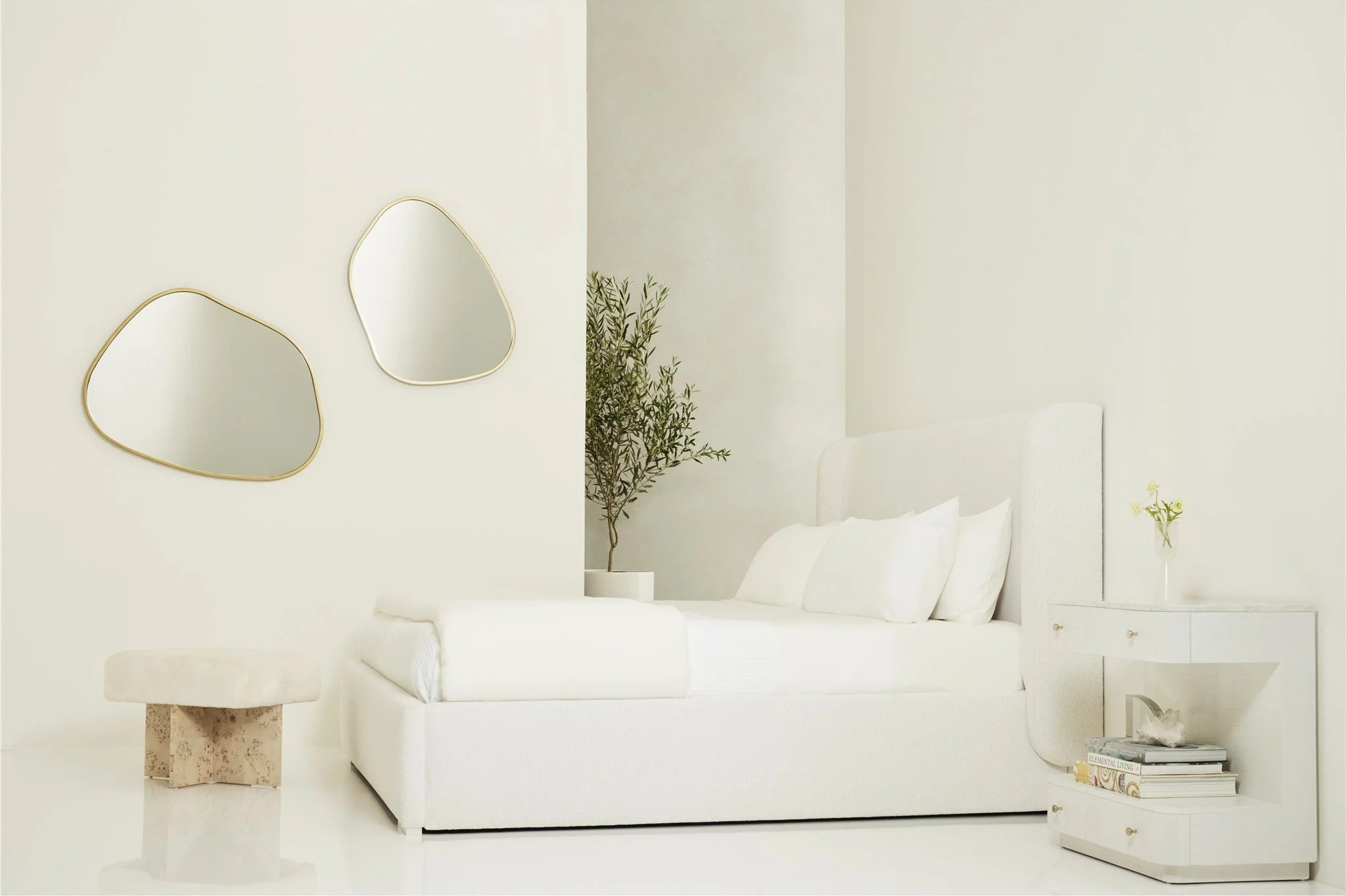 Minimalist living room with a white bed and decorative mirrors.