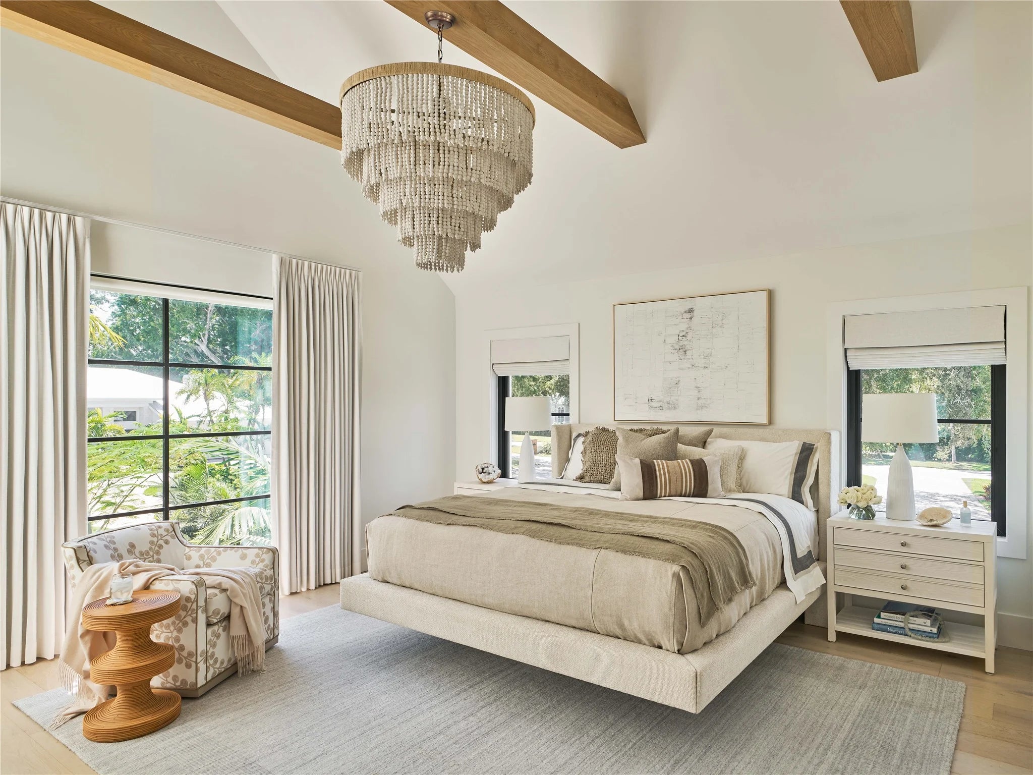 Luxurious bedroom with a chandelier, bed, nightstands, and large windows.