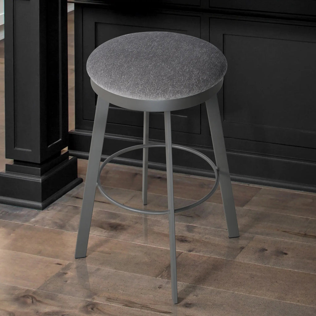 Gray bar stool on a wooden floor with a dark cabinet in the background