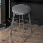 Gray bar stool on a wooden floor with a dark cabinet in the background
