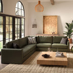 Modern living room with a green sectional sofa, wooden coffee table, and decorative elements.