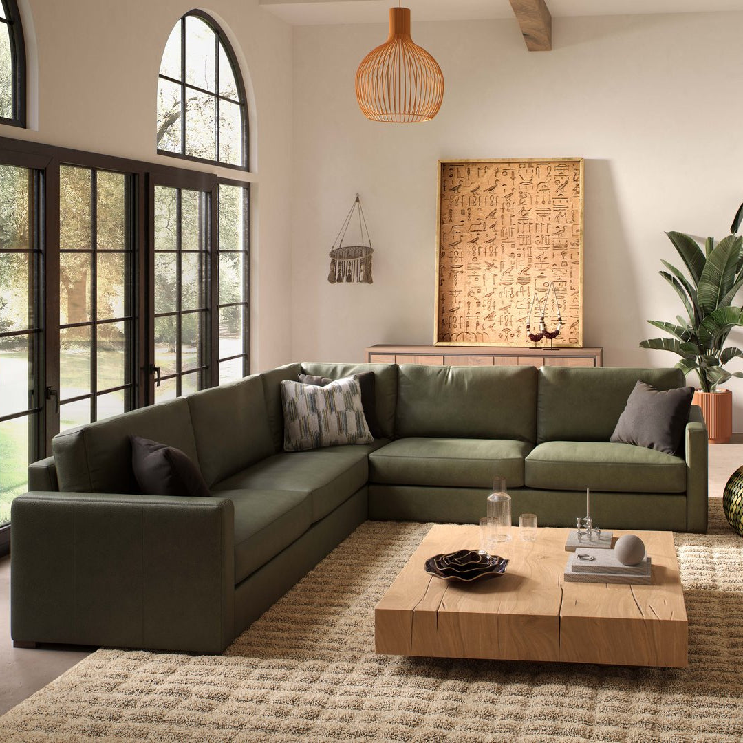 Modern living room with a green sectional sofa, wooden coffee table, and decorative elements.