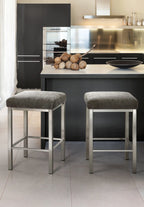 Two gray bar stools in front of a kitchen island with a modern kitchen setup.