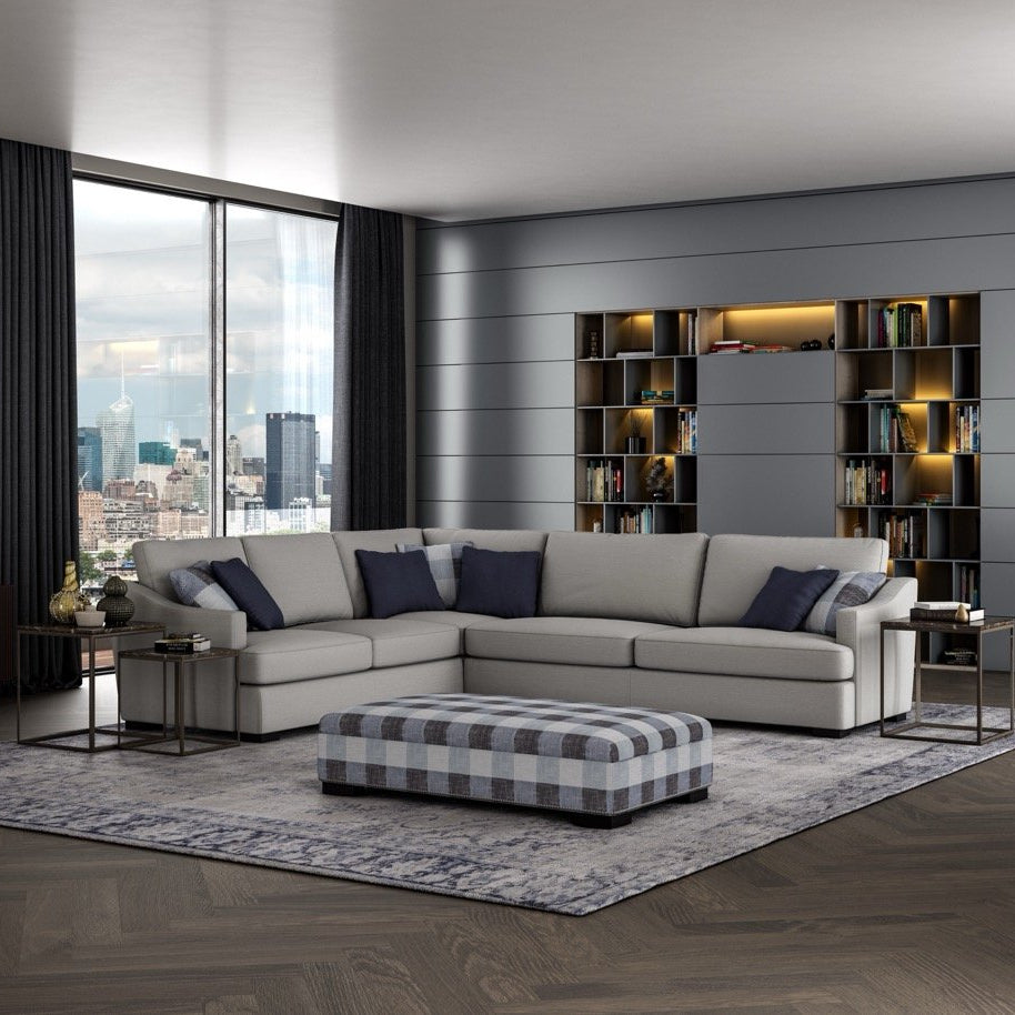 Modern living room with a sectional sofa, ottoman, and bookshelf.